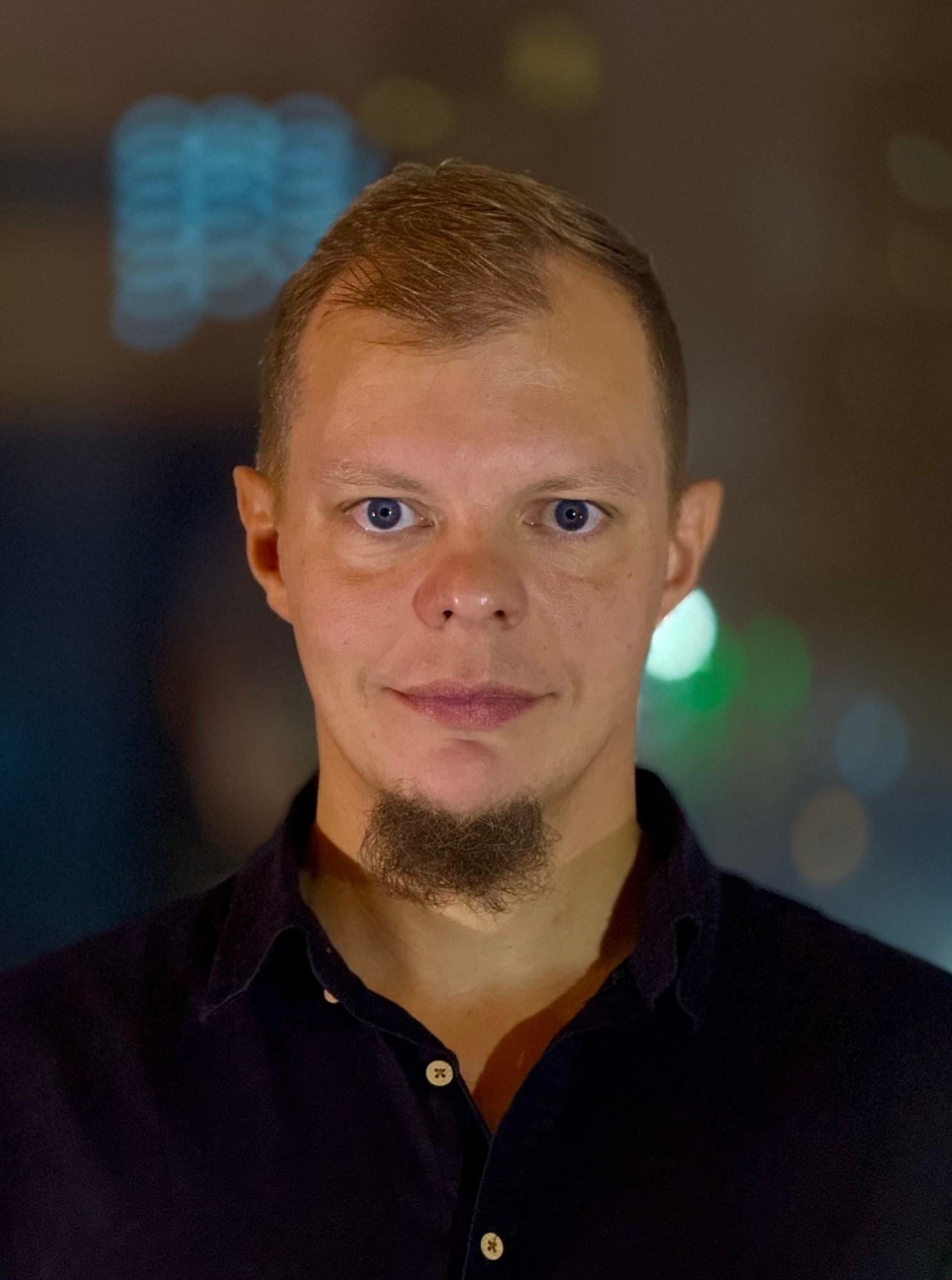 Вячеслав Коншин, портрет в тёмной рубашке на фоне вечерних огней